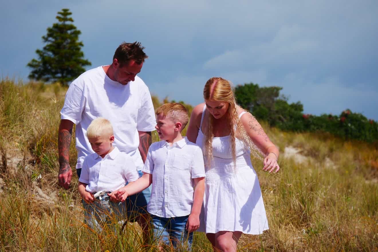 Family walking together through coastal grass during a relaxed session